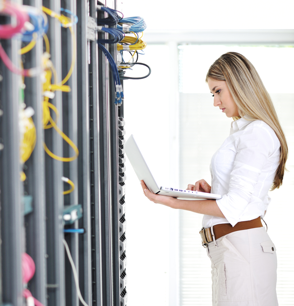 Young female engineer businesswoman with modern laptop in network server room